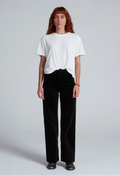 Person wearing a white t-shirt and black pants on a plain background