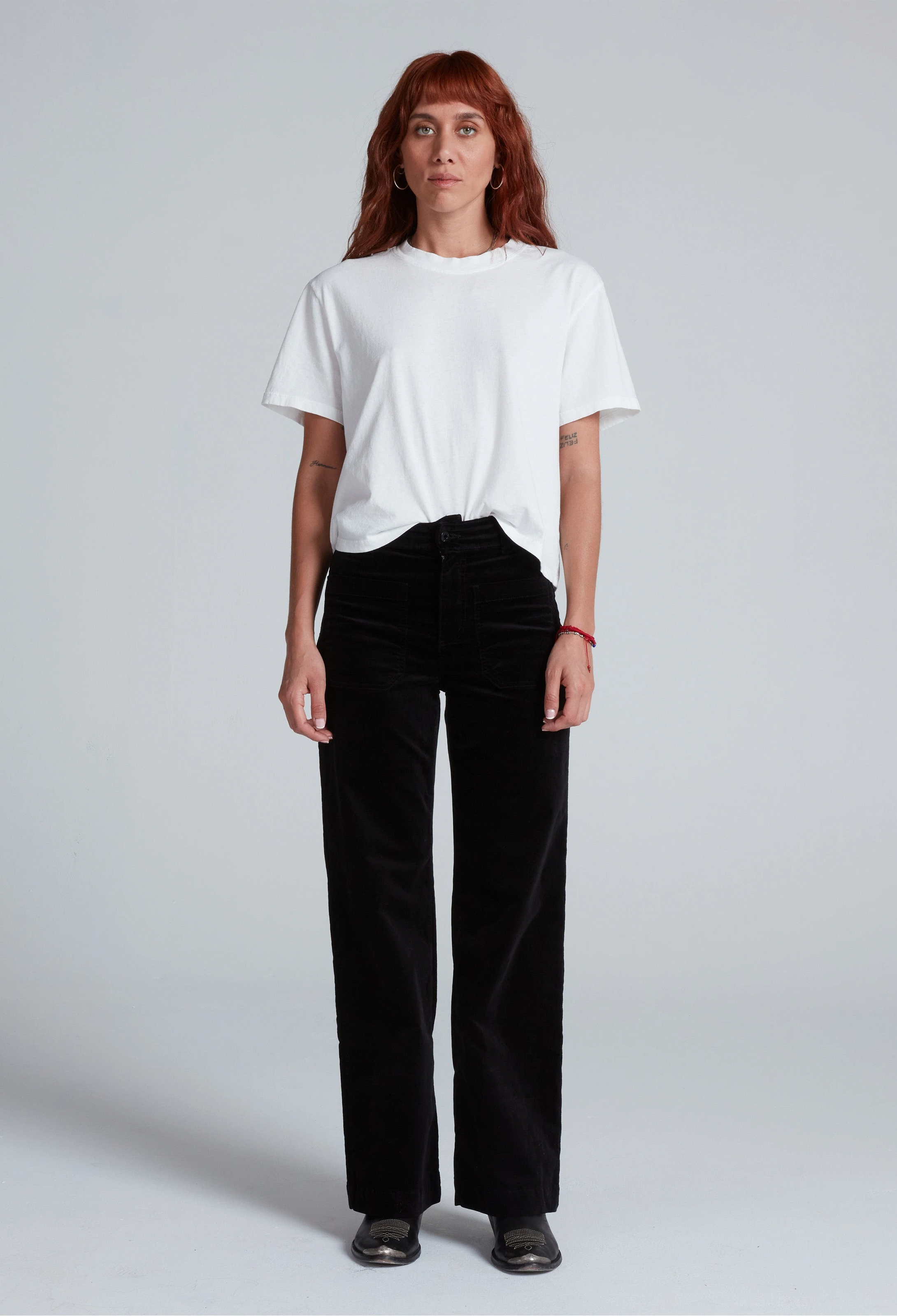 Person wearing a white t-shirt and black pants on a plain background