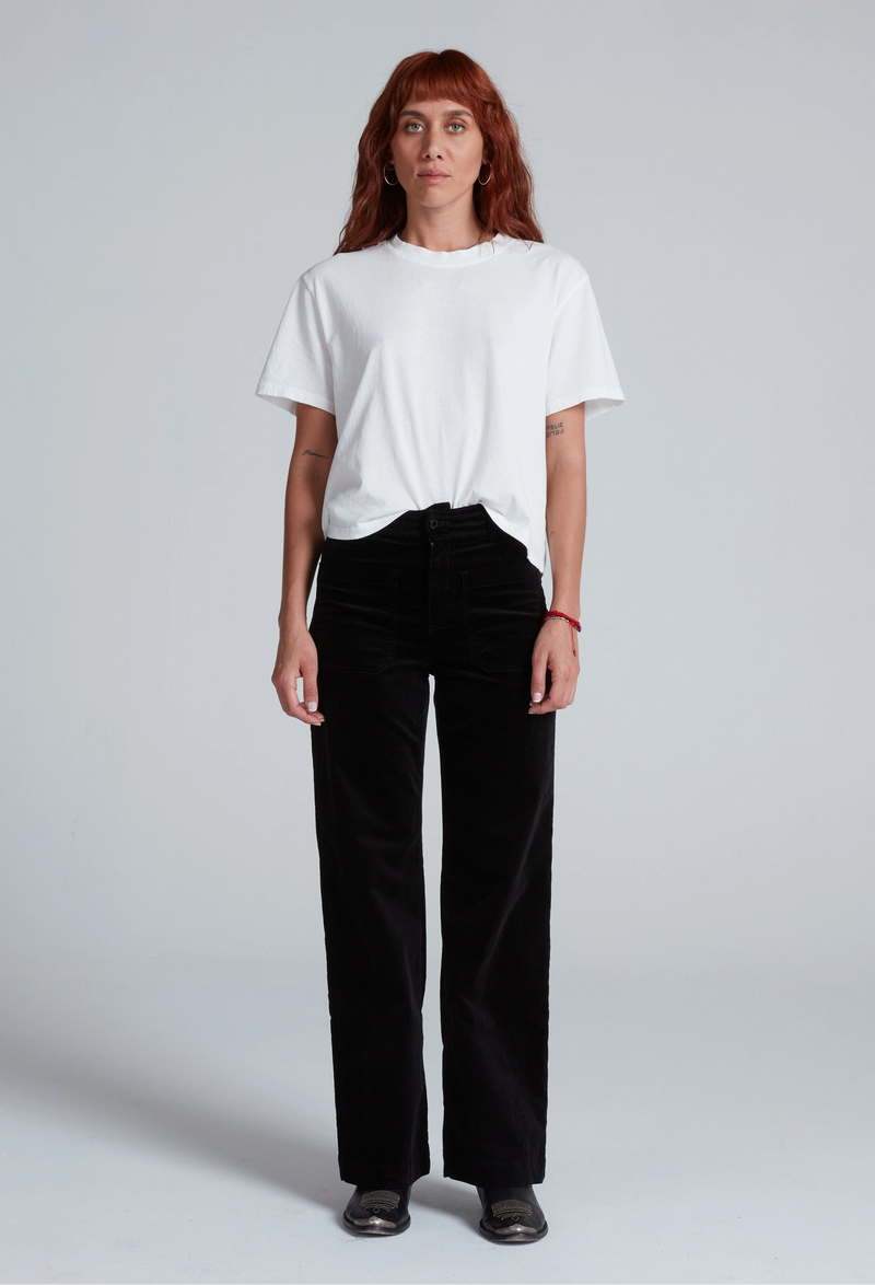 Person wearing a white t-shirt and black pants on a plain background