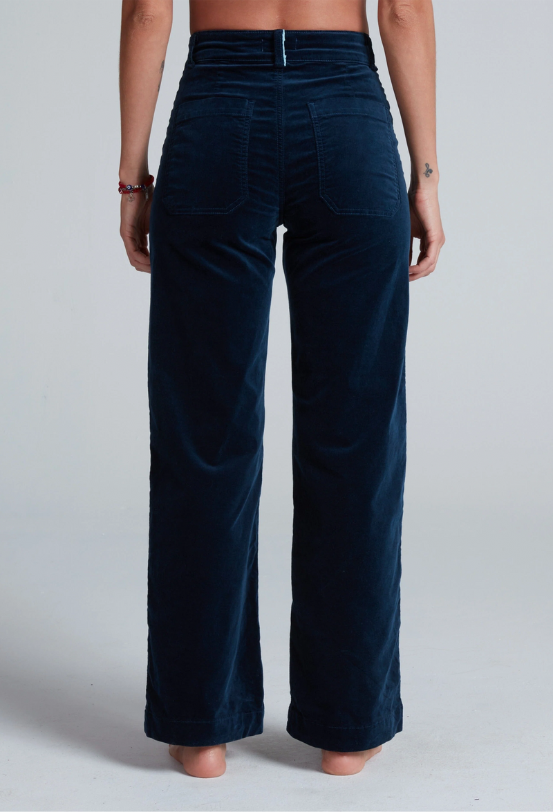 Navy blue velvet pants worn by a person on a plain background