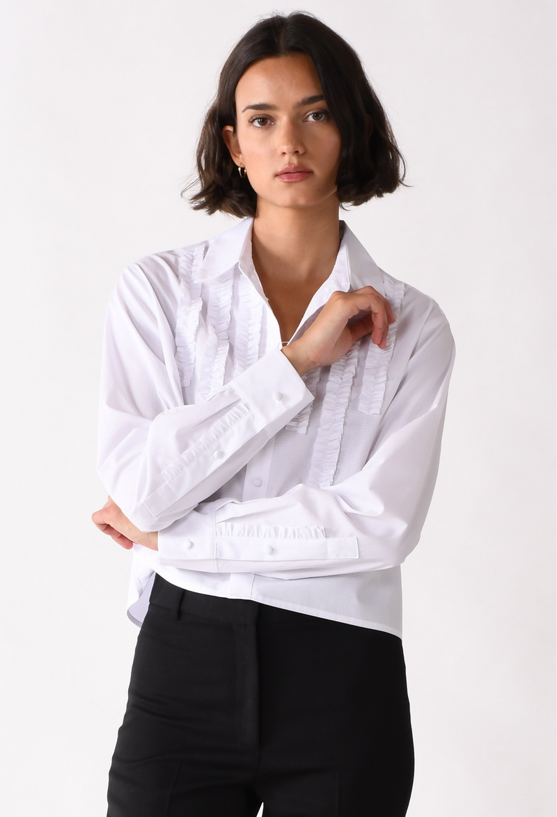 Woman wearing a white shirt with rolled-up sleeves against a white background