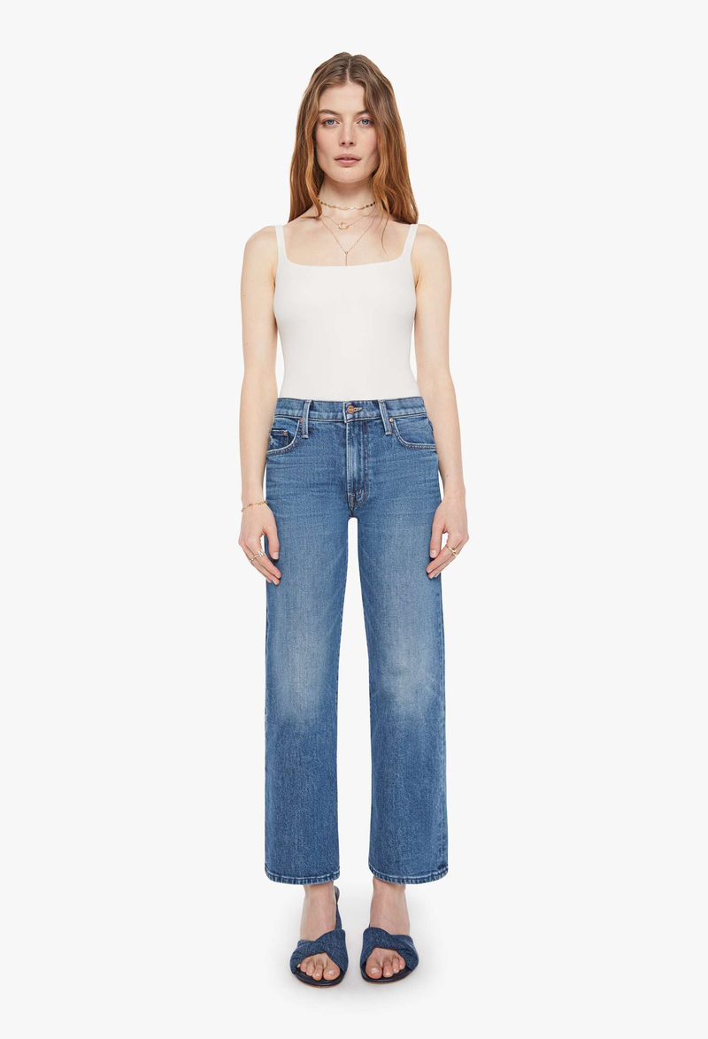 Woman wearing a white tank top and blue jeans on a white background