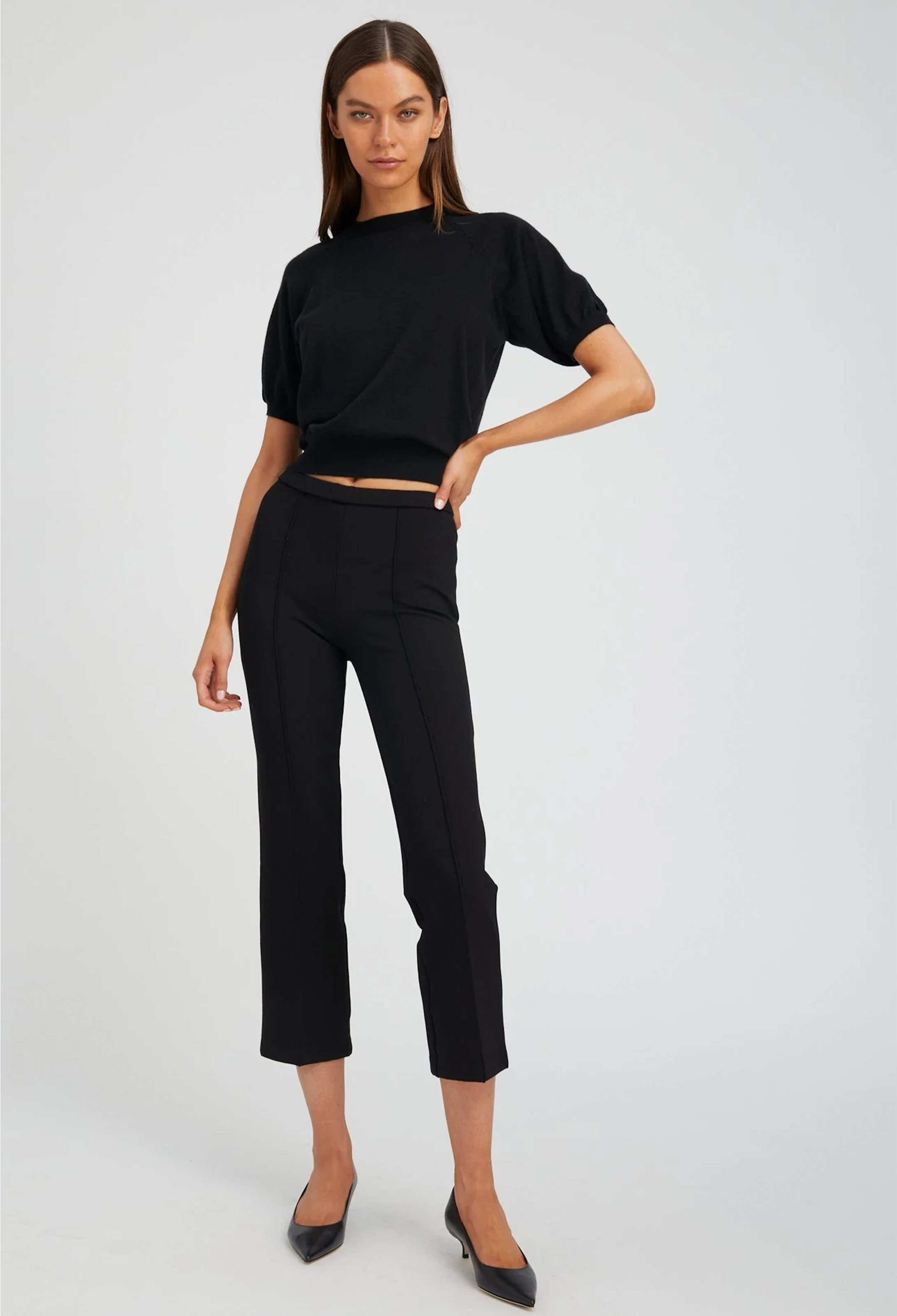 Woman wearing a black top and pants on a white background