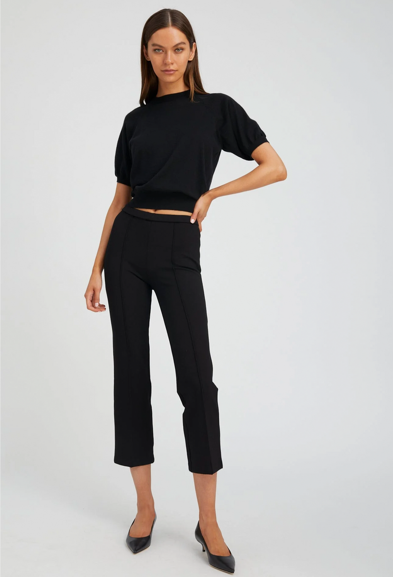 Woman wearing a black top and pants on a white background