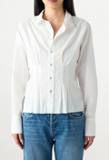 Person wearing a white button-up shirt and blue jeans on a plain background