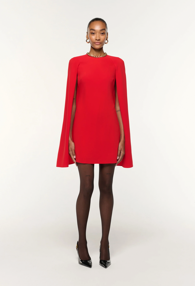Red dress with cape worn by a model on a white background