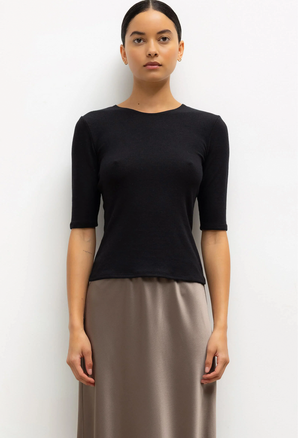 Woman wearing a black top and beige skirt on a white background