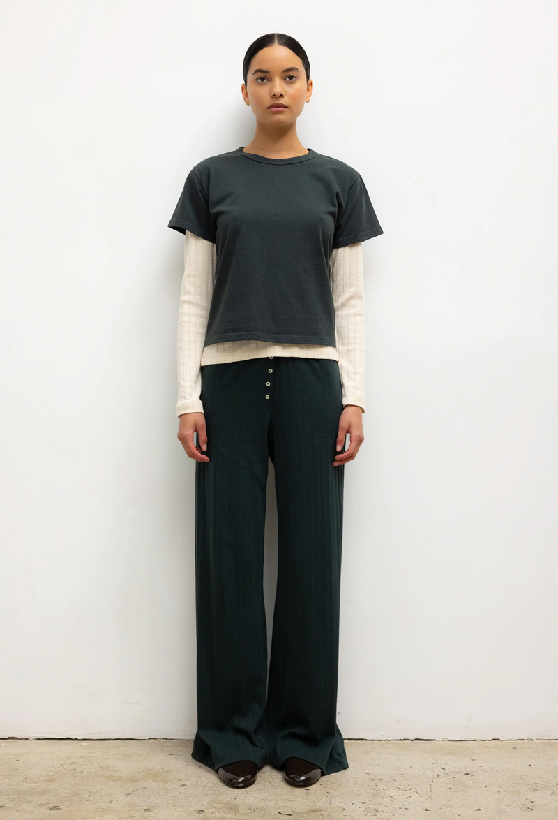 Person wearing a green shirt and dark green pants against a white background