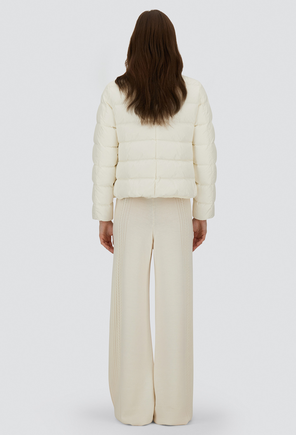 Person wearing a cream puffer jacket and pants on a white background