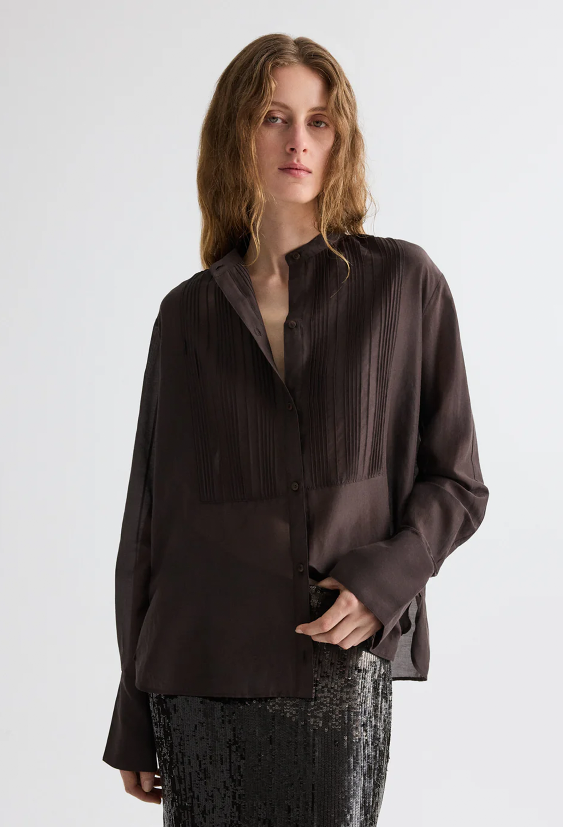 Woman wearing a dark brown blouse with a plain background