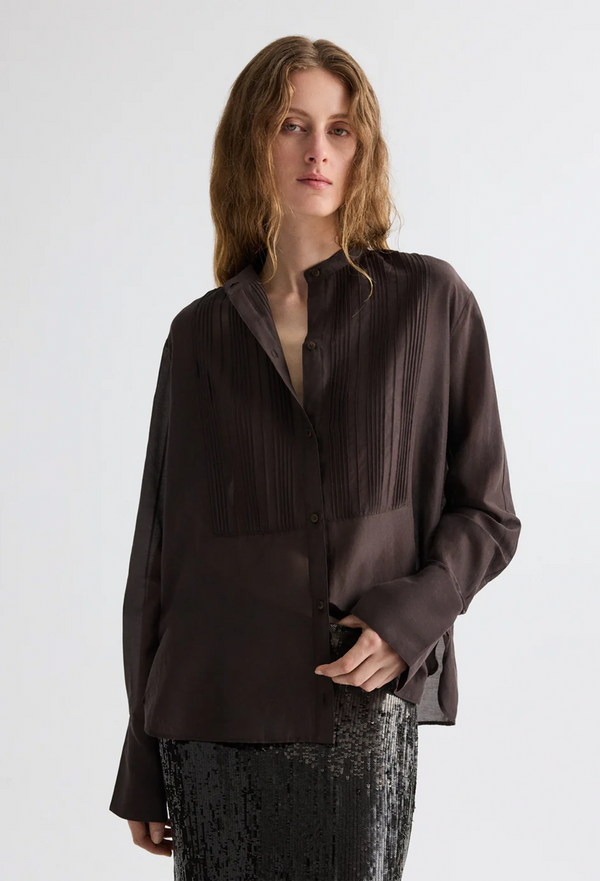 Woman wearing a dark brown blouse with a plain background