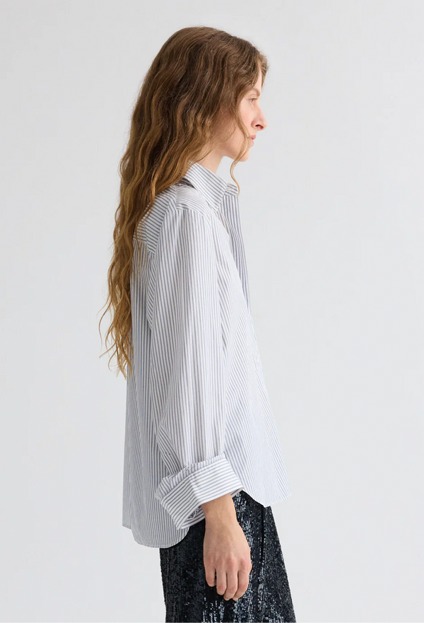 Woman wearing a white shirt with blue stripes against a plain background