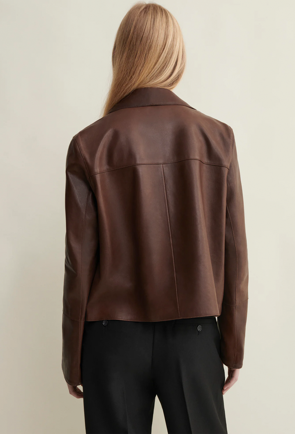 Brown leather jacket worn by a person on a plain background