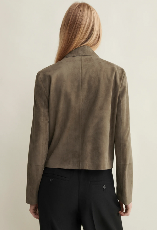 Person wearing a brown suede jacket on a plain background