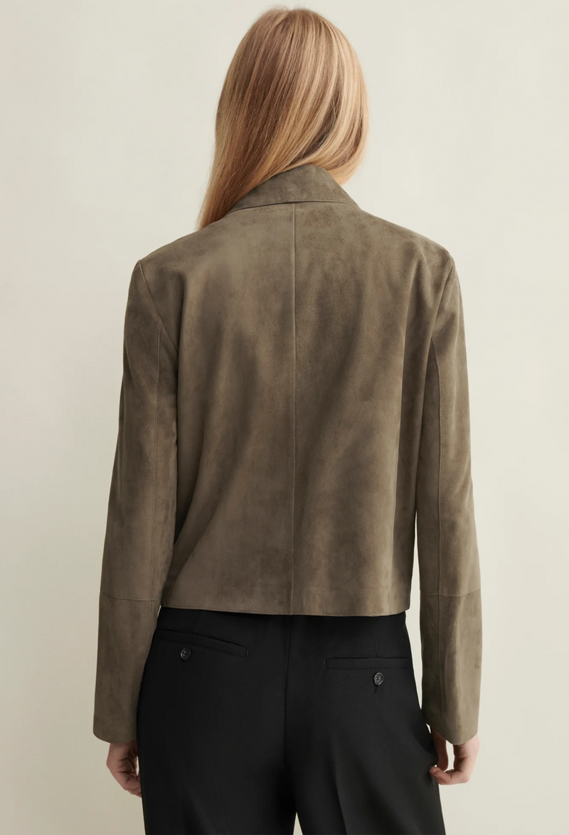 Person wearing a brown suede jacket on a plain background