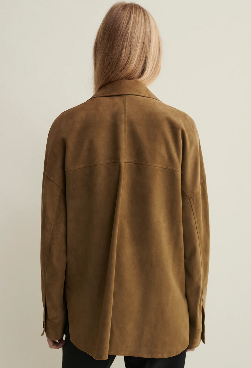 Person wearing a brown suede jacket against a plain background