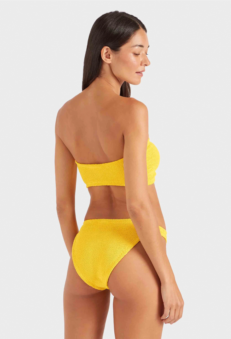 a woman wearing a yellow strapless bikini on a white background