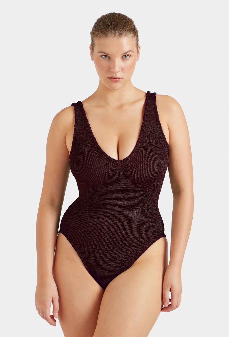 a woman wearing a metallic brown deep V one piece swimsuit on a white background