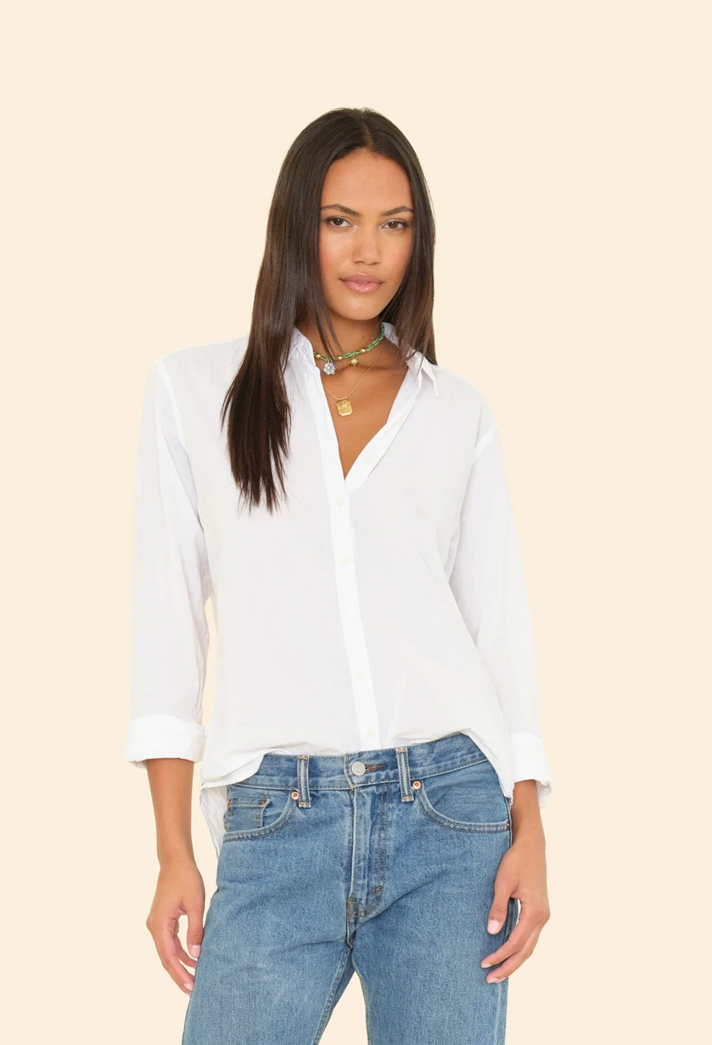 Woman wearing a white shirt and blue jeans on a beige background