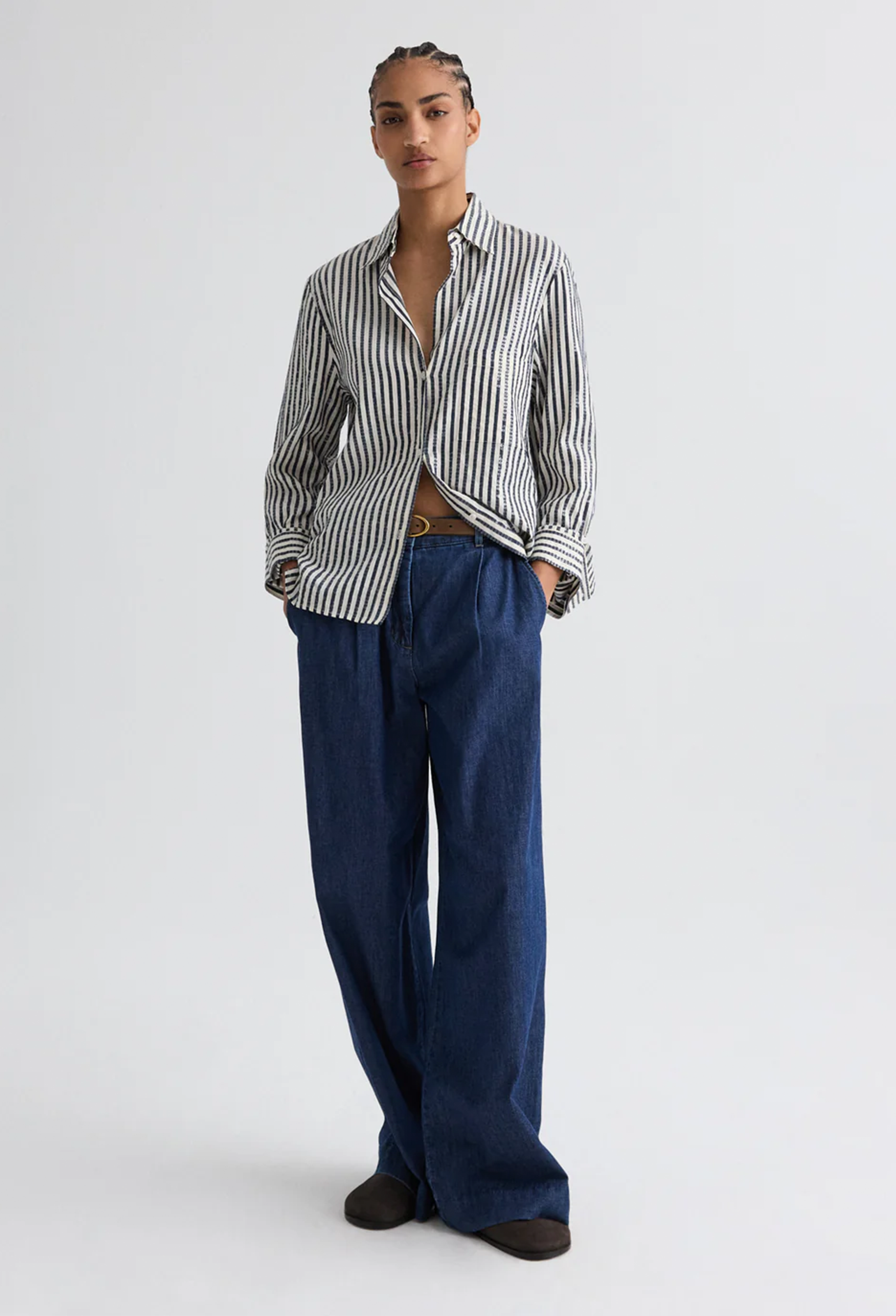 model wearing blue jeans and a striped shirt on a white background