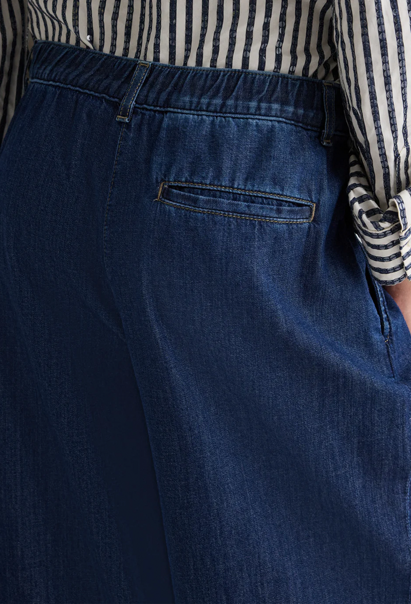 Close-up of blue jeans with a striped shirt in the background