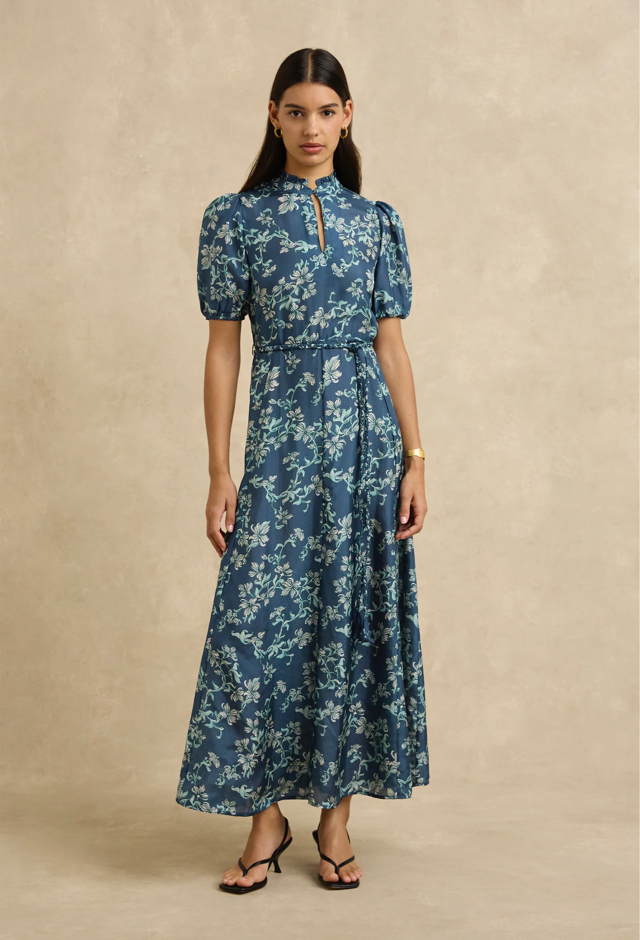 Woman wearing a blue floral dress against a beige background