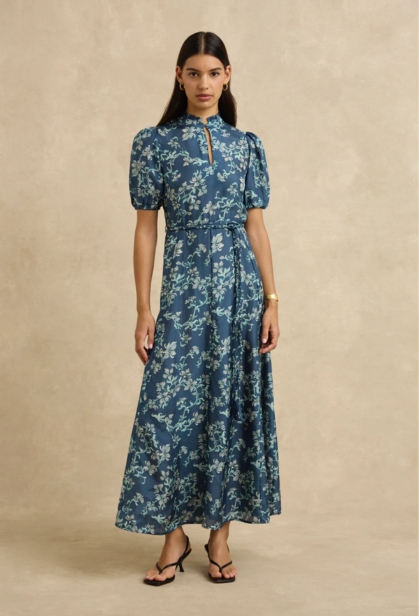 Woman wearing a blue floral dress against a beige background
