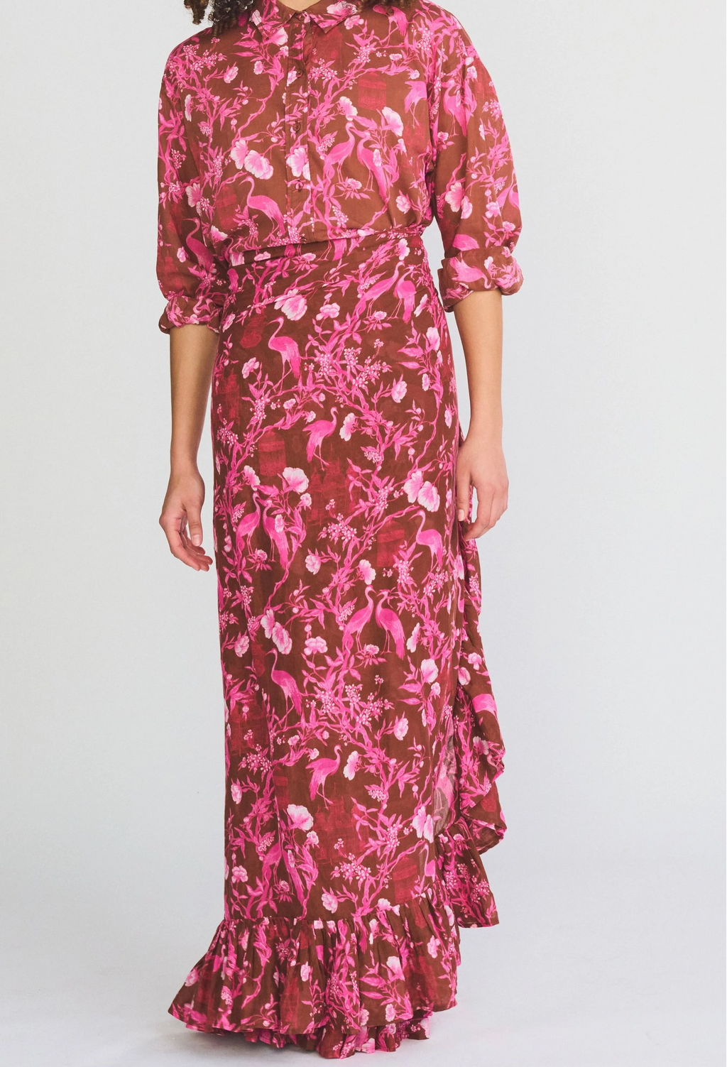 Woman wearing a pink and brown floral dress on a white background