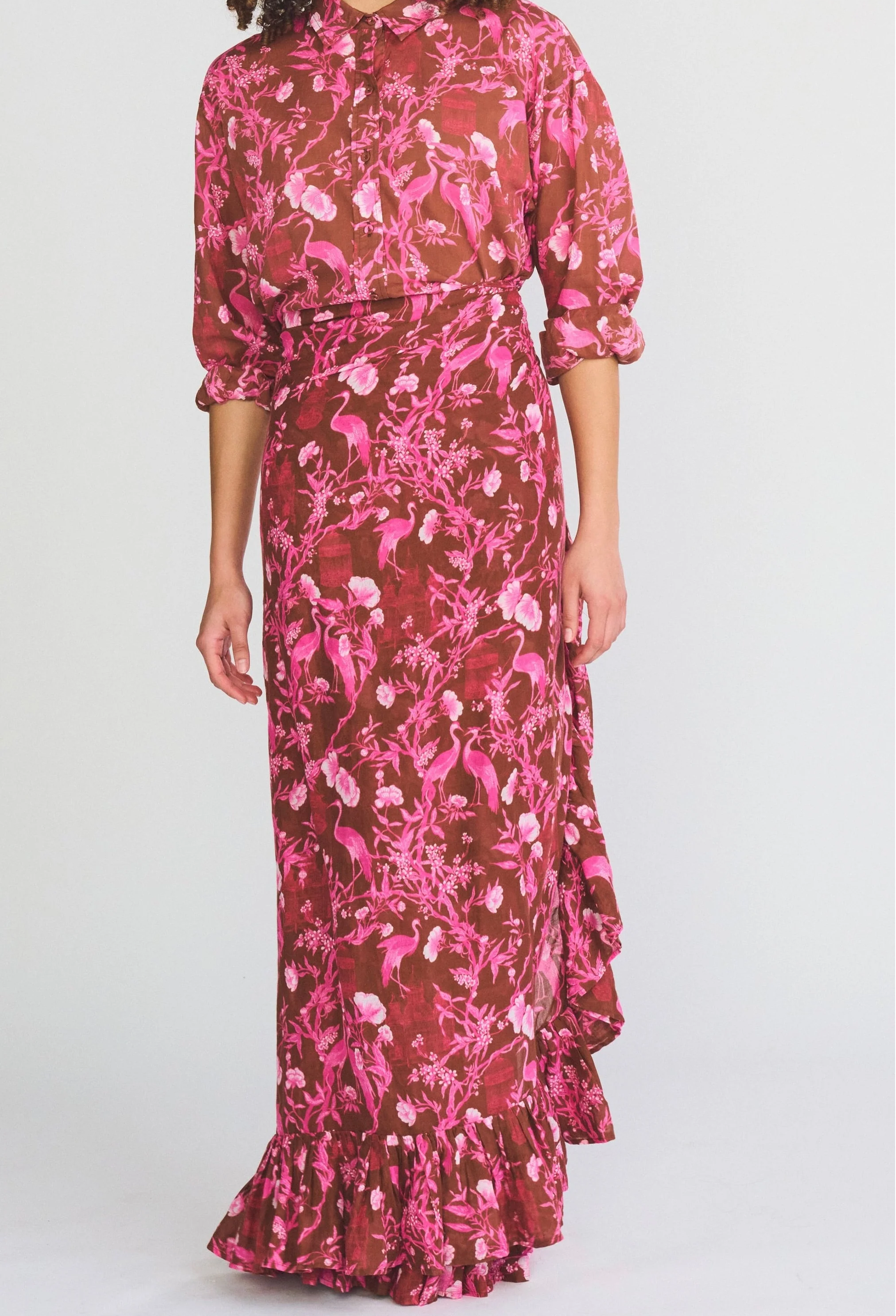 Woman wearing a pink and brown floral dress on a white background