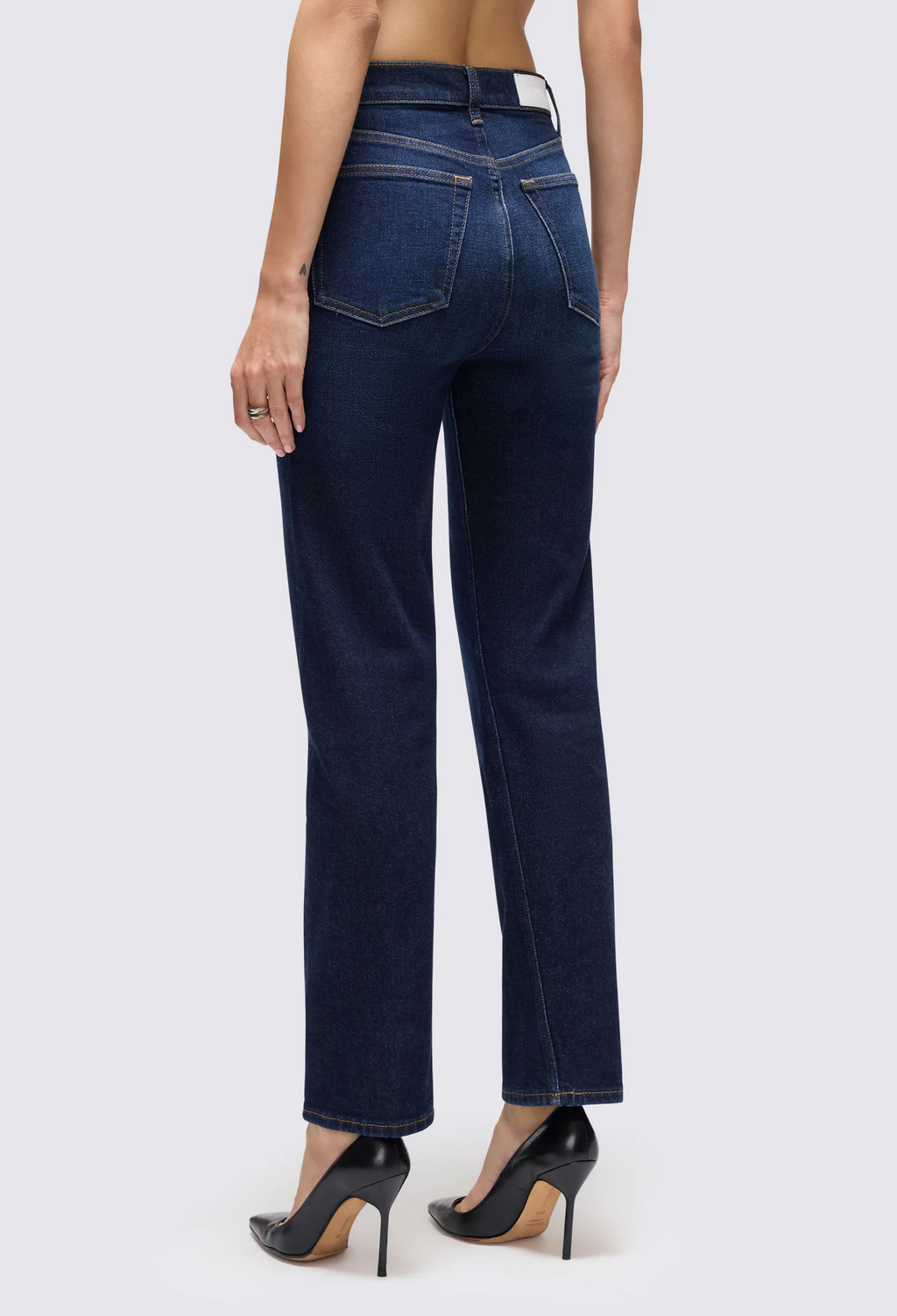 a model wearing dark blue jeans on a white background