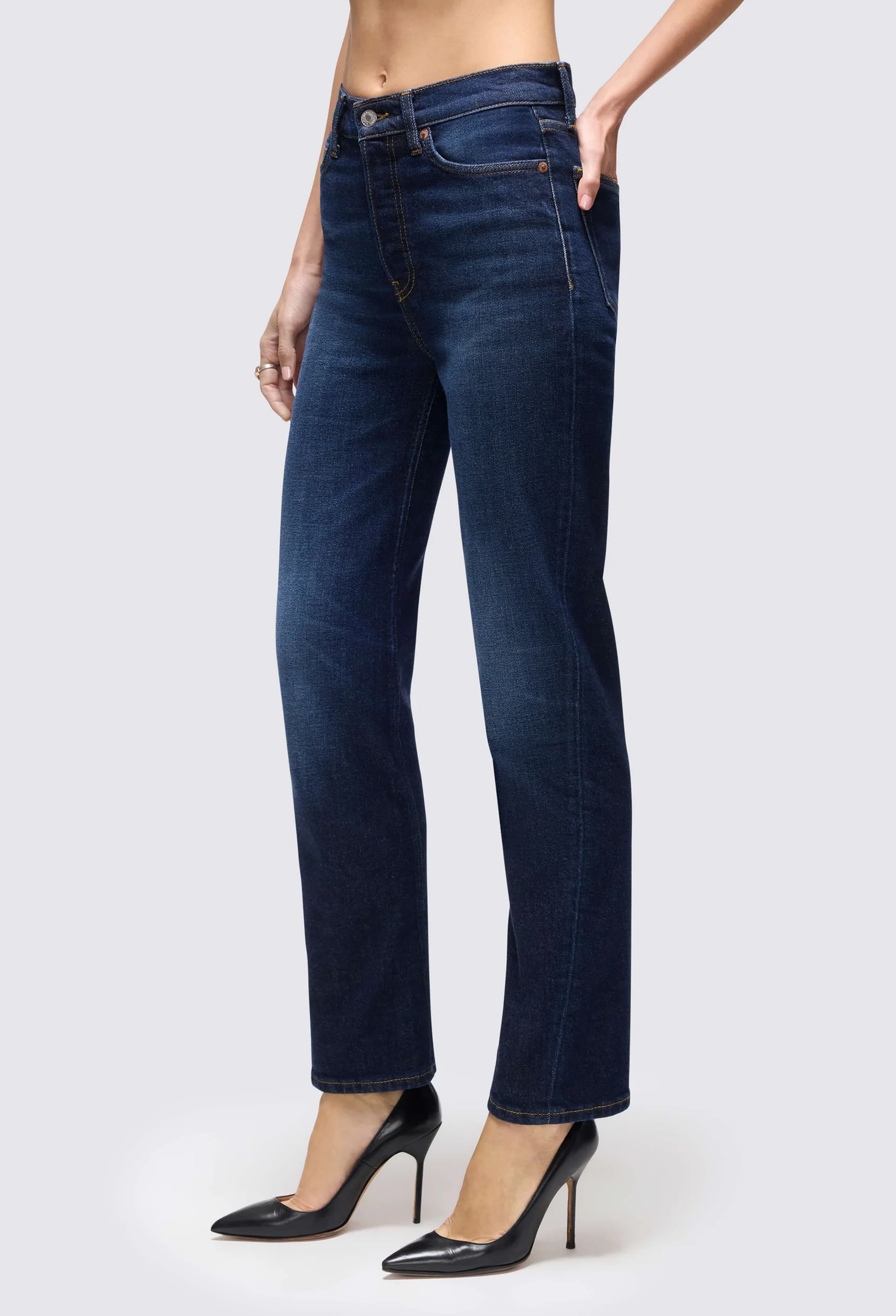 a model wearing dark blue jeans on a white background