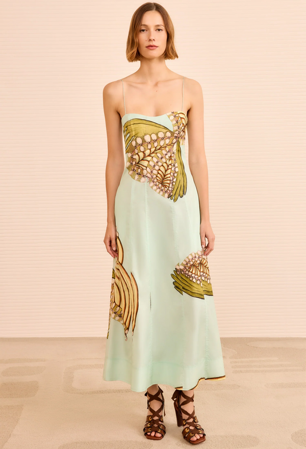 Woman wearing a strapless dress with gold and green floral patterns on a beige background