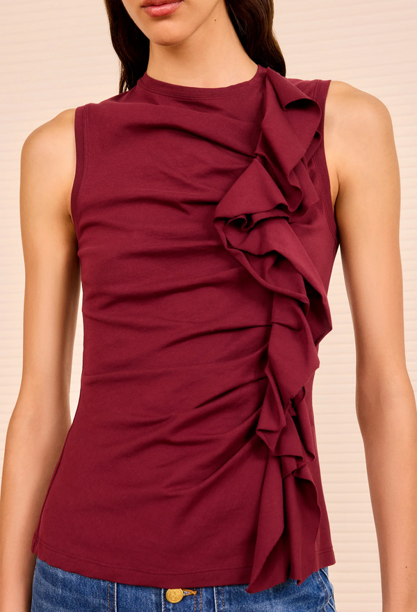 Maroon sleeveless top with ruffles on a beige background