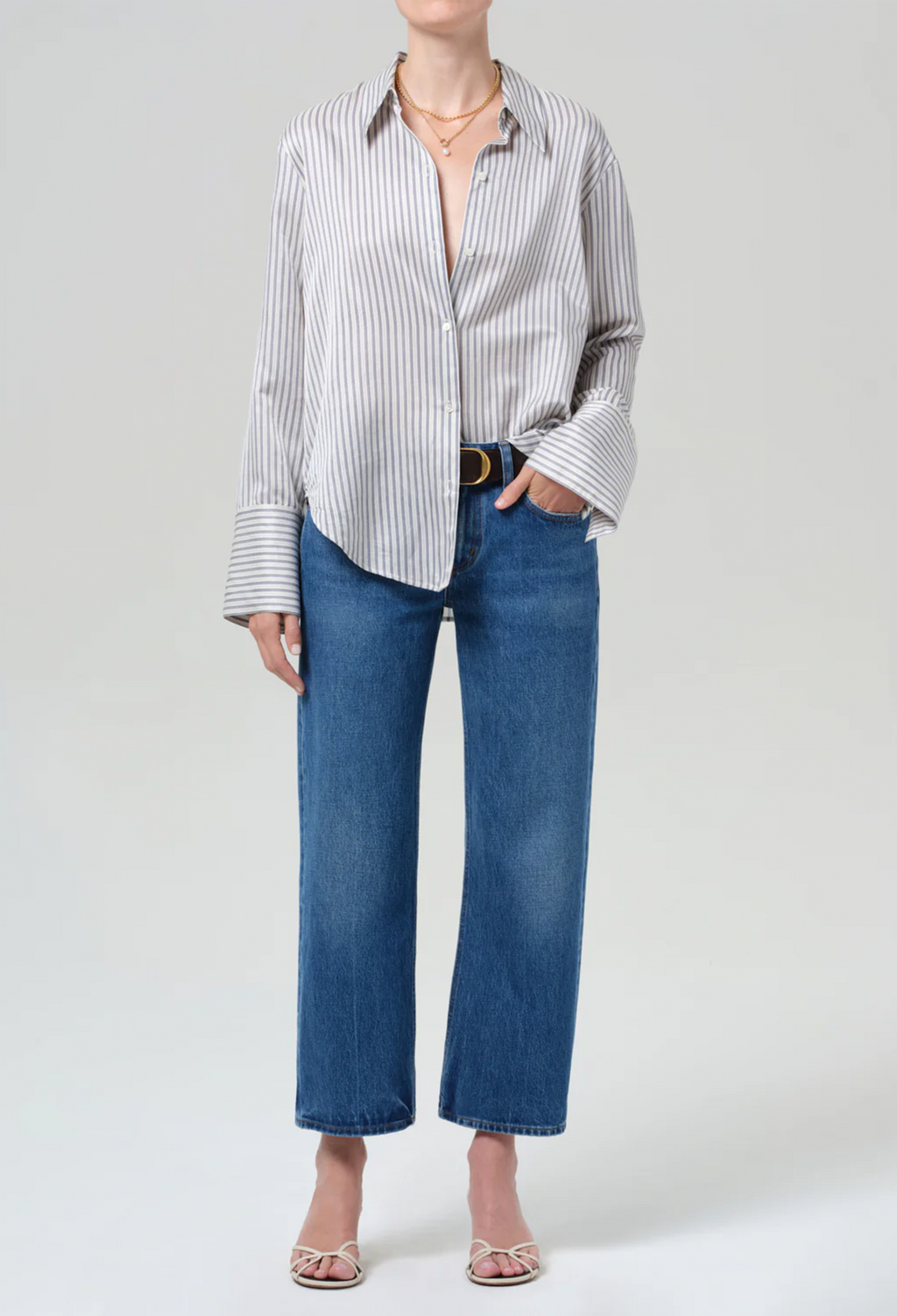 Person wearing a striped shirt and blue jeans on a white background