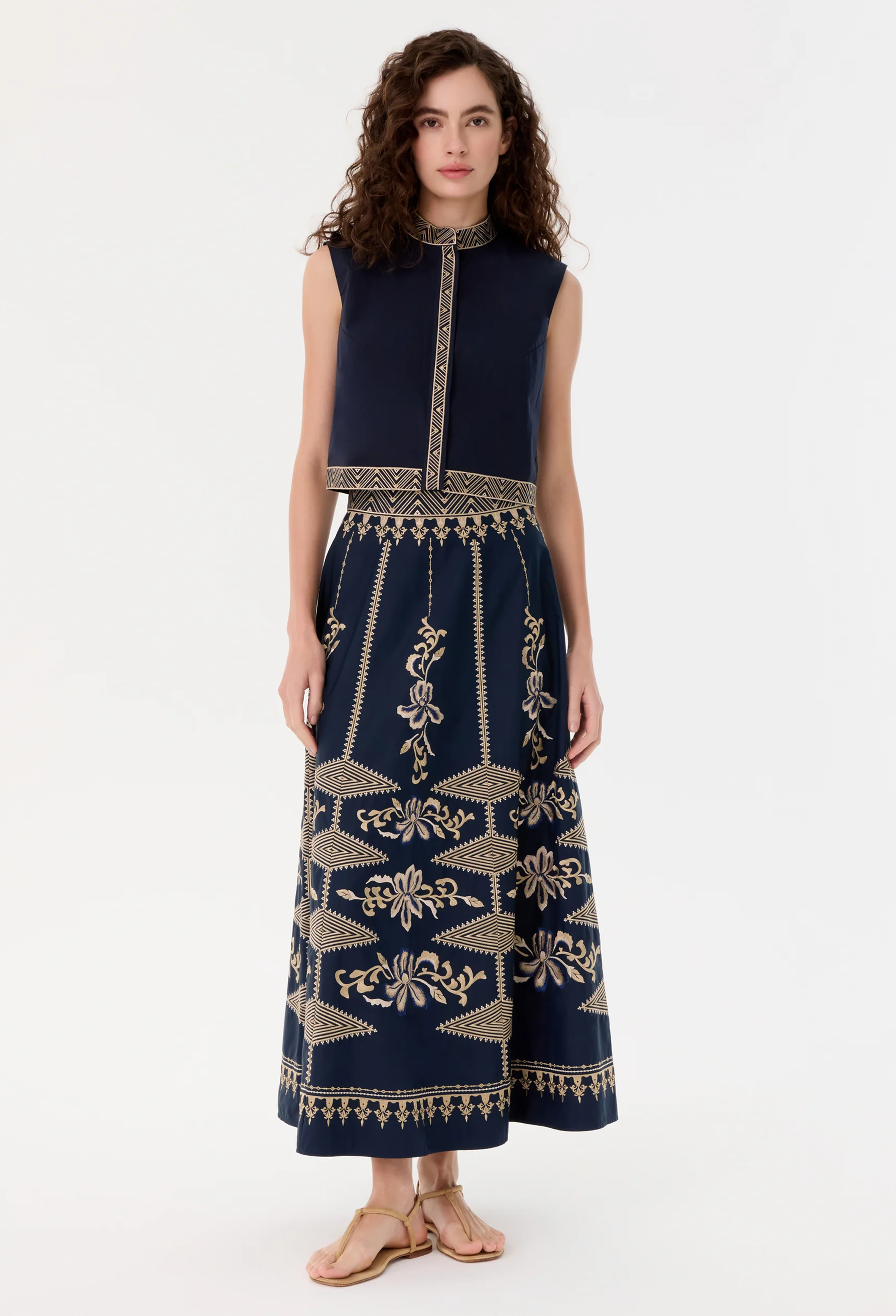 Woman wearing a blue skirt with gold patterns on a white background