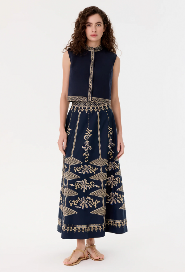 Woman wearing a blue skirt with gold patterns on a white background