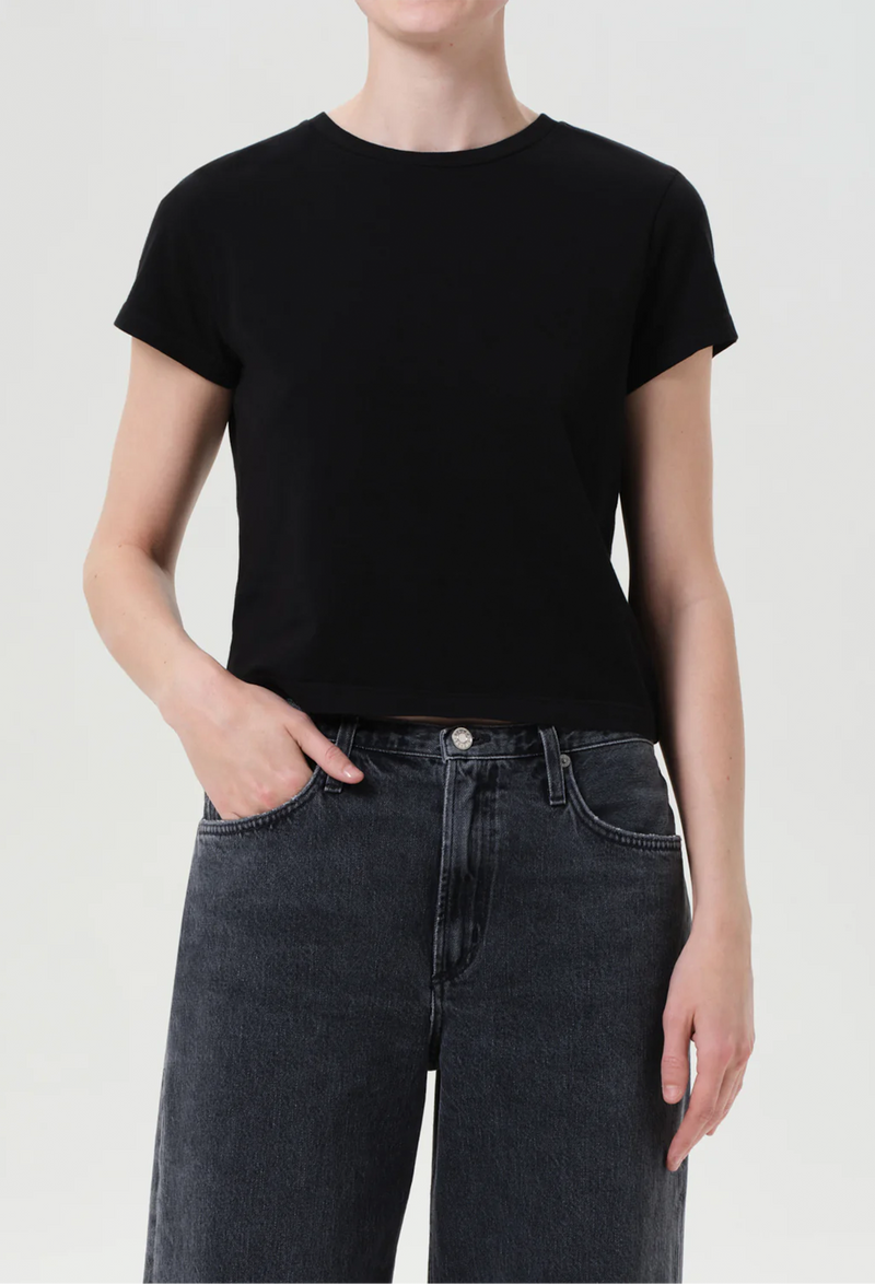Person wearing a black t-shirt and dark jeans on a white background