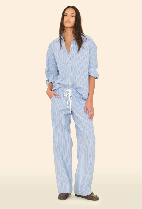 Woman wearing a blue striped pajama set on a beige background