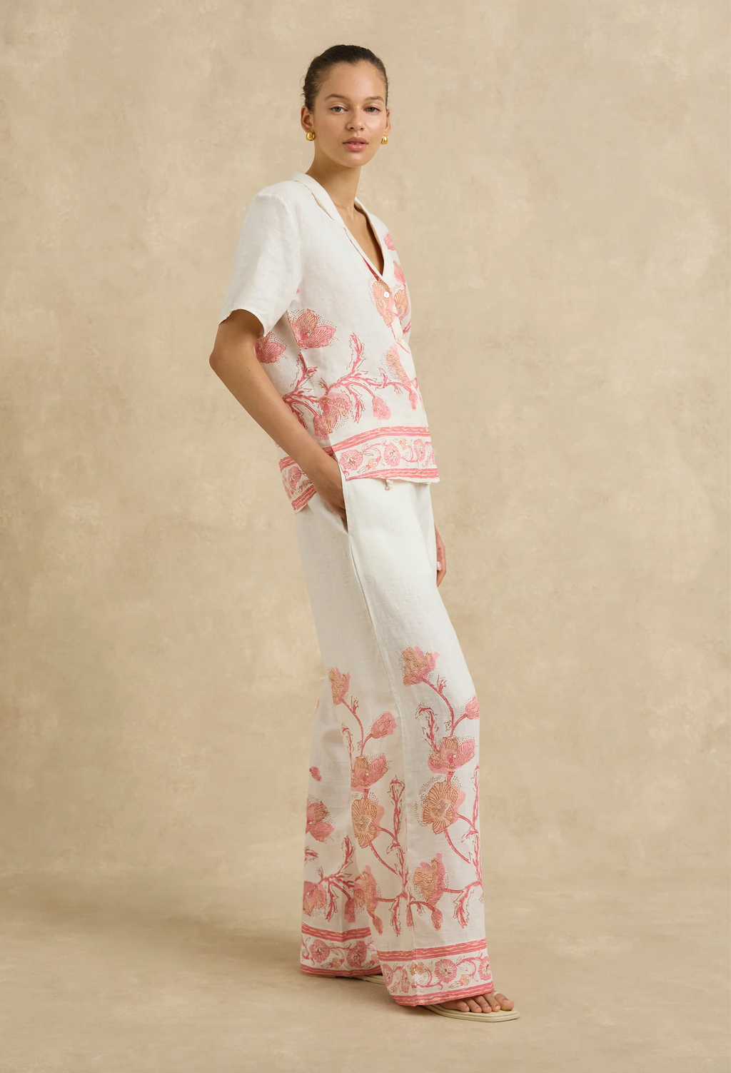 Woman wearing a white outfit with pink floral patterns on a beige background