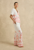 Woman wearing a white outfit with pink floral patterns on a beige background