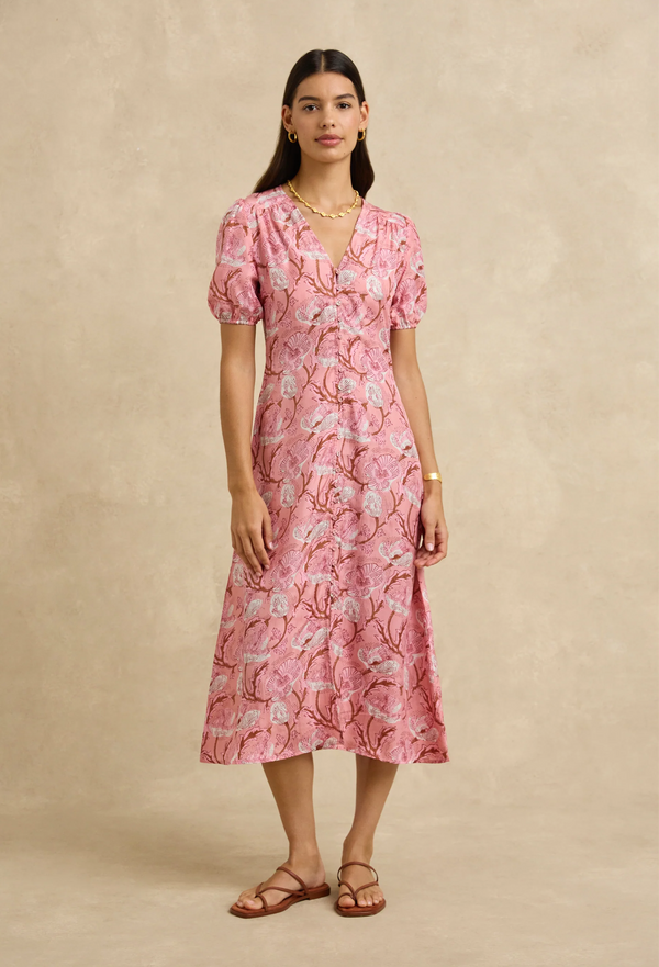 Woman wearing a pink floral dress against a beige background