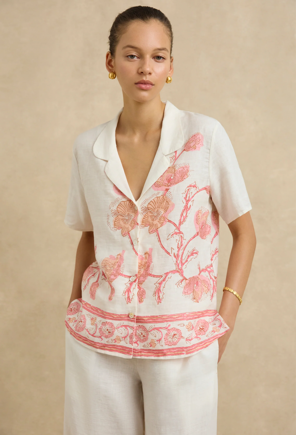 Woman wearing a white blouse with pink floral patterns on a beige background