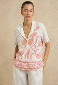 Woman wearing a white blouse with pink floral patterns on a beige background