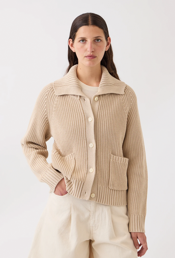 Woman wearing a beige ribbed knit cardigan on a white background