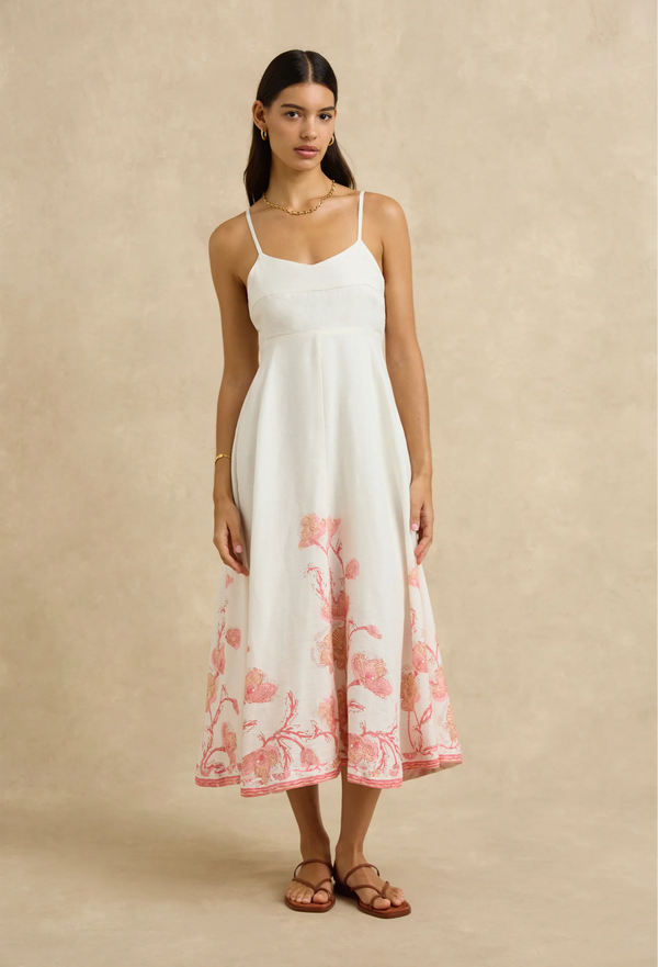 Woman wearing a white dress with pink floral pattern on a beige background