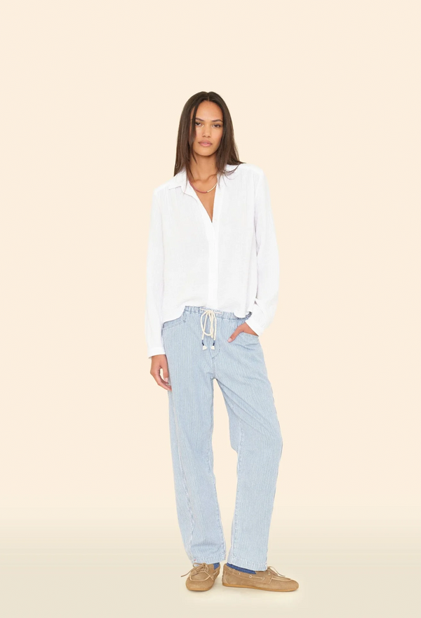 Woman wearing a white blouse and light blue jeans on a beige background