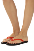 Red flip-flops worn on feet with a white background