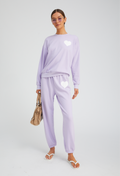 Woman wearing a light purple outfit with heart designs on a white background