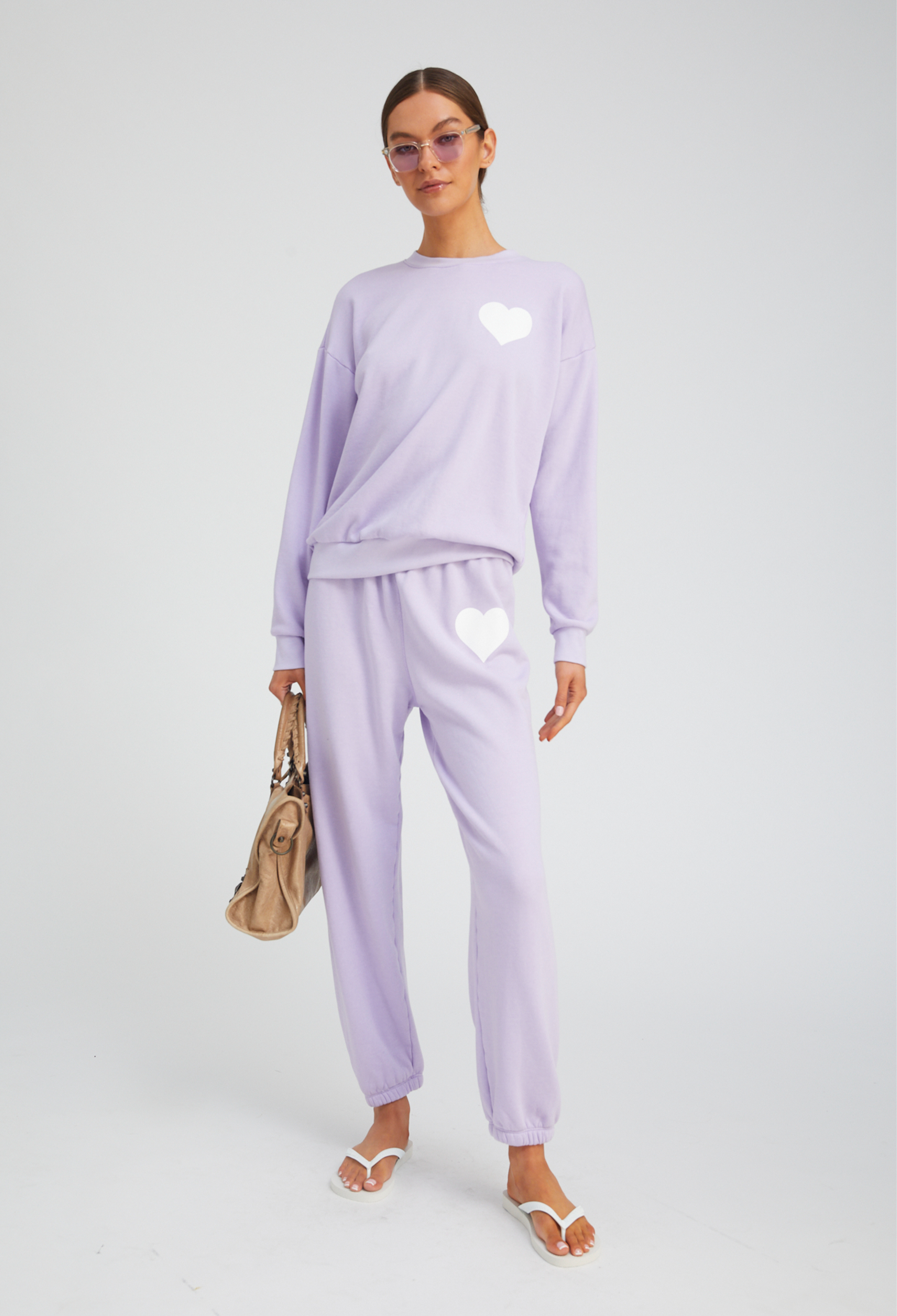 Woman wearing a light purple outfit with heart designs on a white background