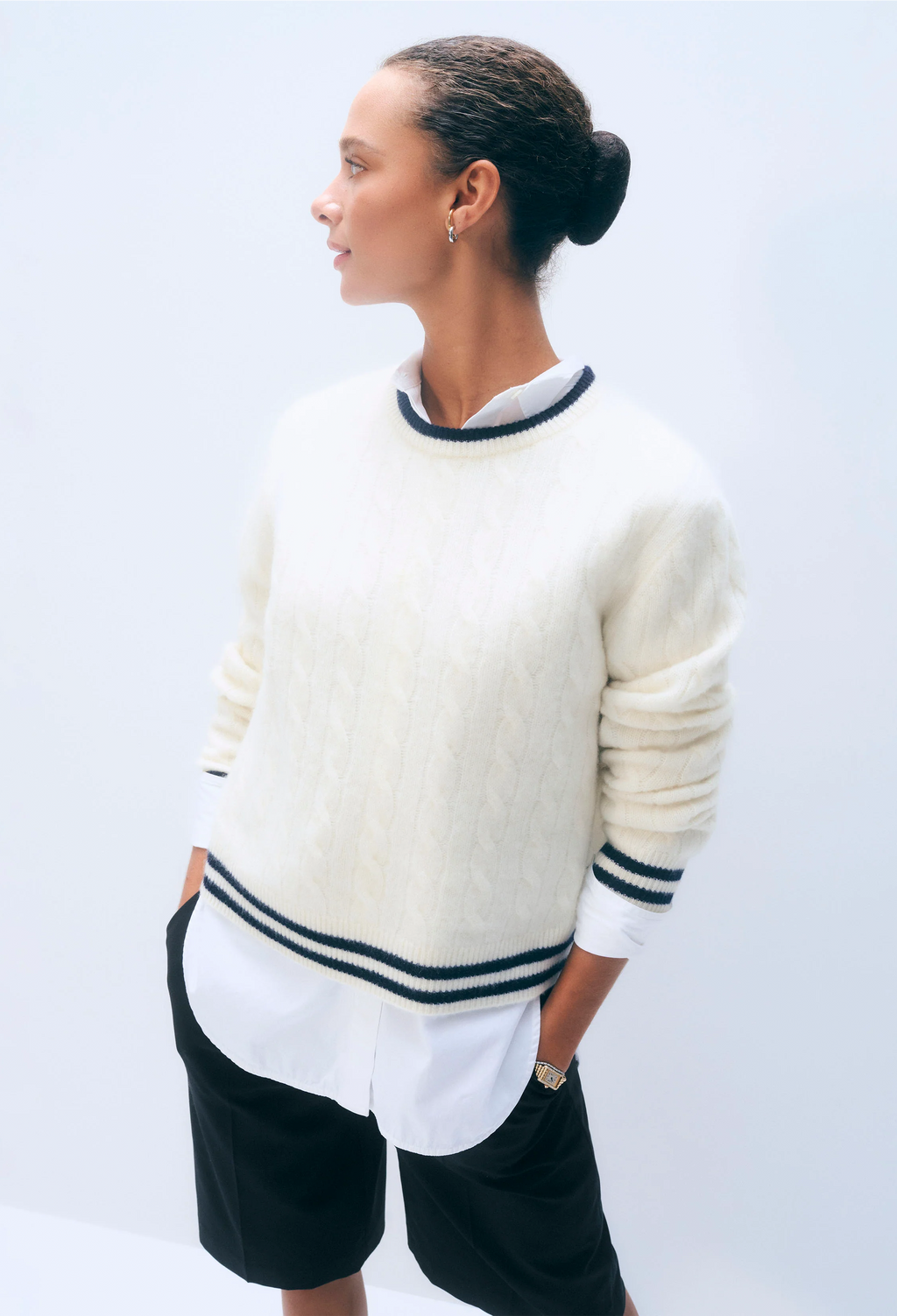 Person wearing a cream sweater with navy stripes on a white background
